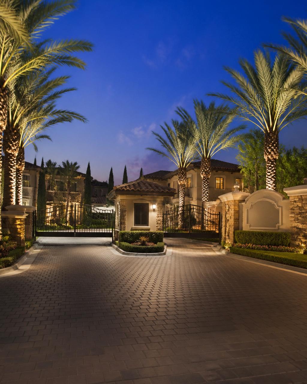 Gated community entrance with guard kiosk and automatic gates at twilight